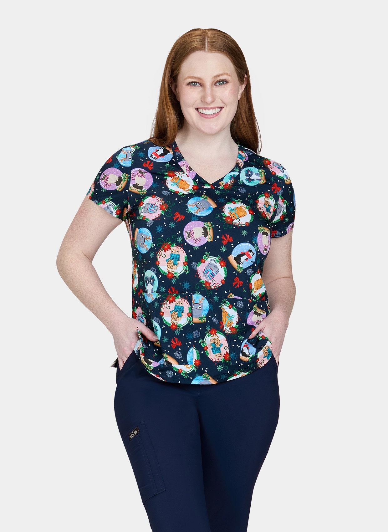 Woman wearing Koi Basics Leslie scrub top with colourful holiday cat print.