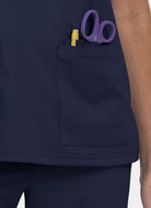 Koi Cureology Cardi Scrub Top - Navy blue scrub top with a pocket containing purple scissors and a yellow pen.